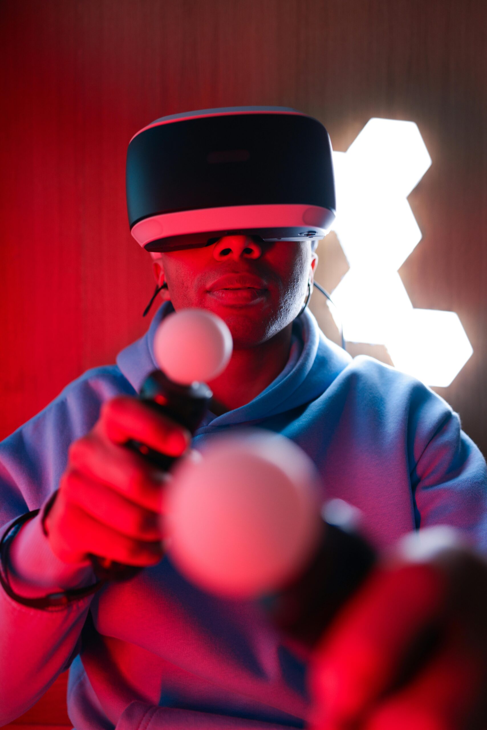 Person using VR headset and controllers in a glowing red atmosphere, showcasing modern virtual reality gaming.